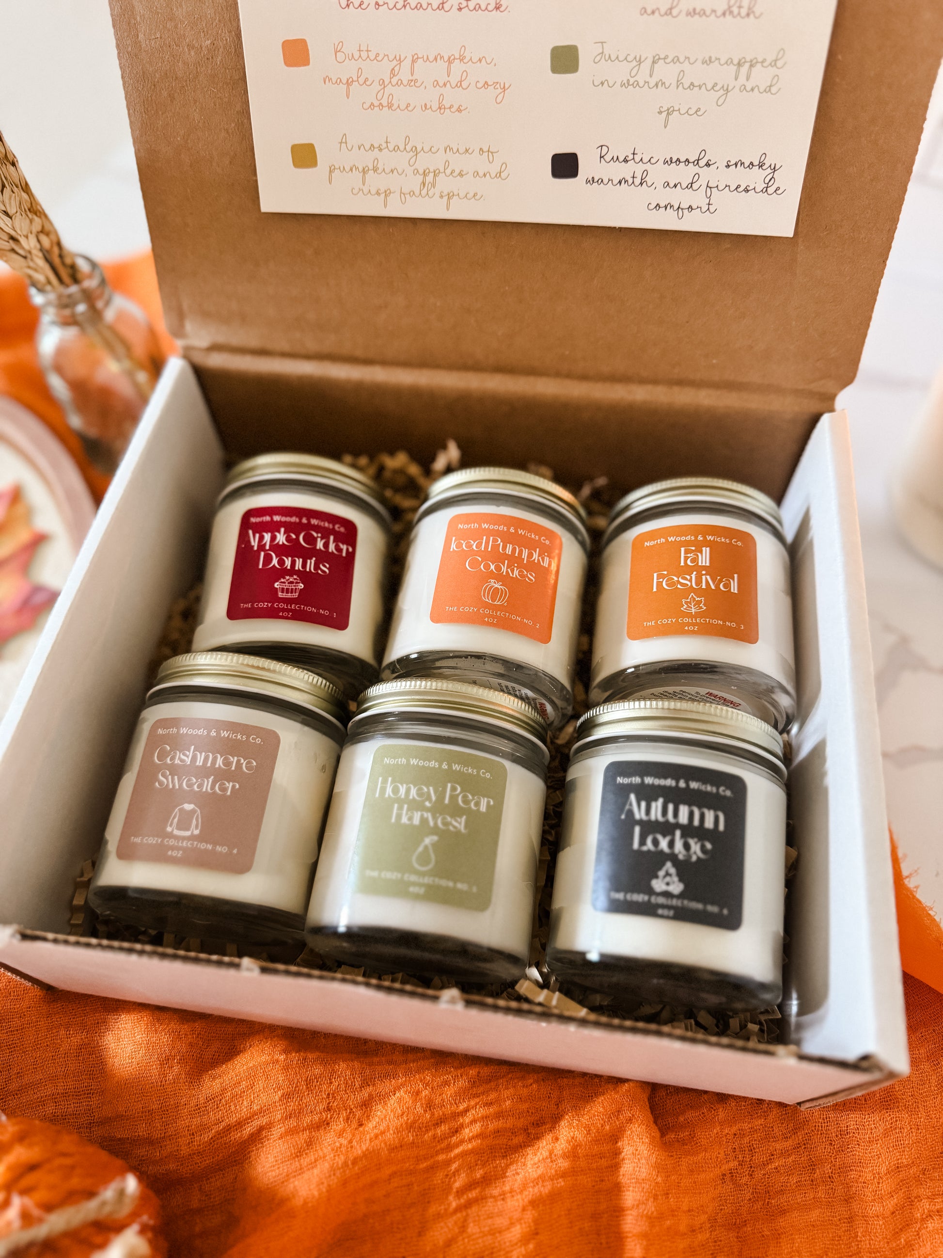 Set of six small candles in a box with labels on an orange surface